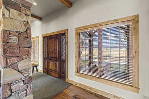 Entryway with wood-type flooring and beam ceiling