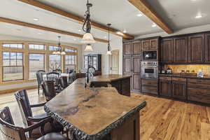 Kitchen with stainless steel oven, a large island, decorative light fixtures, and sink