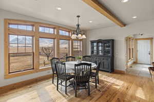 Dining area featuring an inviting chandelier, vaulted ceiling with beams, a wealth of natural light, and light hardwood / wood-style floors