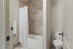 Bathroom with shower / bath combination with curtain and toilet