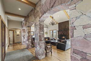 Unfurnished living room featuring a chandelier, a fireplace, beam ceiling, and light hardwood / wood-style flooring