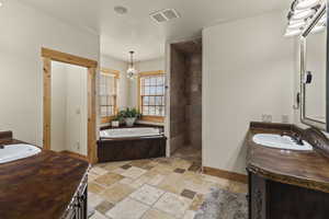 Bathroom with a notable chandelier, vanity, and a tub