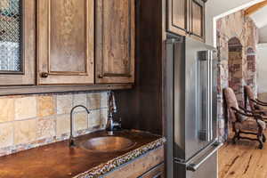 Kitchen with tasteful backsplash, high quality fridge, sink, and dark brown cabinetry