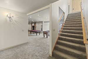 Stairs featuring a fireplace, billiards, and carpet