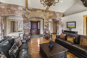 Living room featuring vaulted ceiling with beams, light hardwood / wood-style flooring, and a chandelier