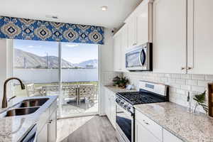 Kitchen featuring sink, white cabinetry, light stone counters, appliances with stainless steel finishes, and a mountain view