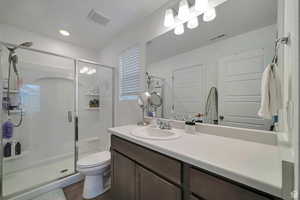 Bathroom with vanity, a shower with door, and toilet