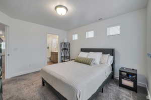 Carpeted bedroom with connected bathroom and a textured ceiling