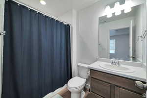 Bathroom with vanity, hardwood / wood-style floors, and toilet