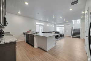 Kitchen featuring sink, light hardwood / wood-style flooring, and light stone countertops