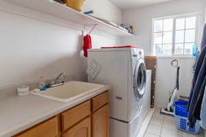 Laundry room featuring cabinets, light tile flooring, and sink