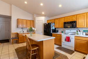 Kitchen with a kitchen bar, a center island, light tile floors and vaulted ceilings