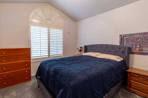 Bedroom featuring carpet flooring and vaulted ceiling