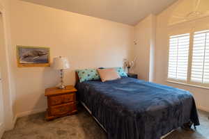 Bedroom featuring carpet flooring and vaulted ceiling