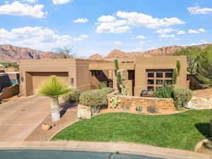 Pueblo revival-style home with a garage, a mountain view, and a front lawn