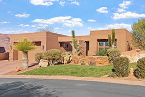 Pueblo revival-style home featuring a garage and a front yard