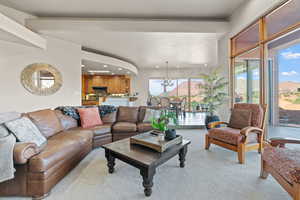 Living room with light colored carpet, a healthy amount of sunlight, and a chandelier