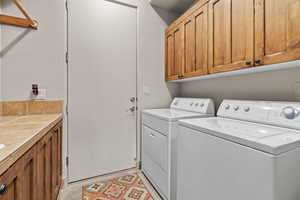 Washroom with washer and clothes dryer, cabinets, and light tile patterned flooring