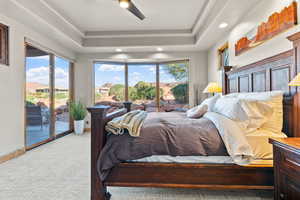 Bedroom featuring light carpet, access to outside, a raised ceiling, and ceiling fan