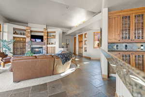 Living room with built in shelves, a fireplace, and vaulted ceiling