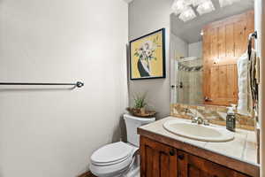 Bathroom with vanity, a shower with shower door, tasteful backsplash, and toilet