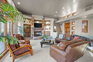 Living room with a fireplace, built in shelves, and carpet floors