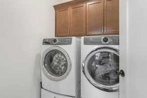 Washroom with cabinets and washing machine and clothes dryer