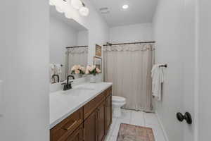 Bathroom featuring walk in shower, vanity, toilet, and tile patterned flooring