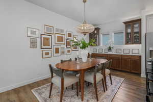 Dining area with dark wood-type flooring and a notable chandelier