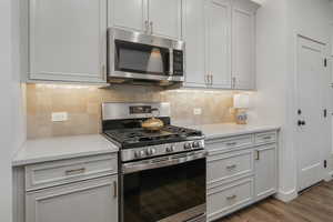 Kitchen featuring hardwood / wood-style floors, decorative backsplash, and appliances with stainless steel finishes