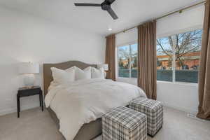 Carpeted bedroom with multiple windows and ceiling fan