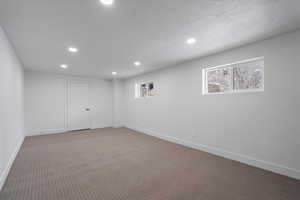 Basement with carpet floors and a textured ceiling