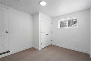 Unfurnished bedroom featuring light carpet, a textured ceiling, and a closet