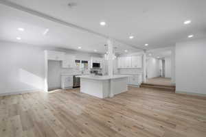 Kitchen featuring white cabinetry, stainless steel appliances, a center island, and light hardwood / wood-style floors