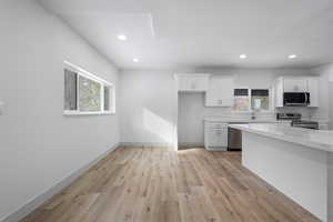 Kitchen with white cabinetry, appliances with stainless steel finishes, a wealth of natural light, and light hardwood / wood-style flooring