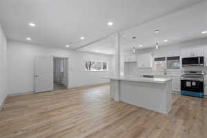 Kitchen featuring white cabinetry, stainless steel appliances, light hardwood / wood-style floors, and a kitchen island