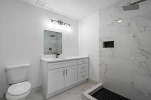 Bathroom featuring vanity, a tile shower, a textured ceiling, and toilet