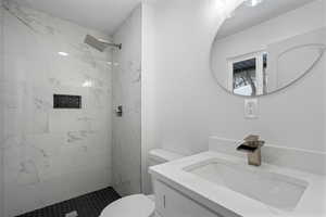 Bathroom featuring vanity, toilet, and tiled shower