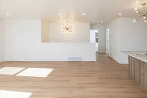 Empty room featuring a chandelier and light wood-type flooring