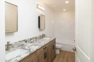 Full bathroom featuring wood-type flooring, shower / washtub combination, vanity, and toilet