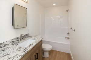 Full bathroom with vanity, wood-type flooring, shower / washtub combination, and toilet