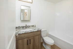 Full bathroom with hardwood / wood-style flooring, vanity, shower / washtub combination, and toilet