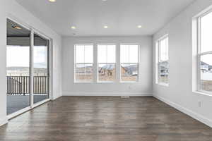 Unfurnished room featuring a healthy amount of sunlight and dark hardwood / wood-style flooring