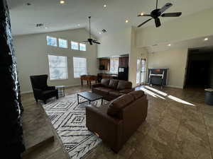 Living room featuring ceiling fan and high vaulted ceiling