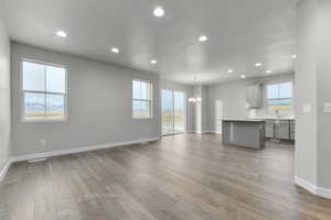 Unfurnished living room with plenty of natural light, a chandelier, sink, and light hardwood / wood-style flooring