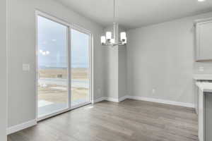 Unfurnished dining area featuring light hardwood / wood-style flooring and a notable chandelier