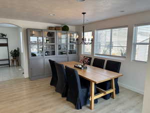 Dining space featuring a textured ceiling, light hardwood / wood-style floors, and a chandelier