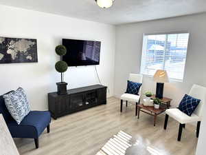 Sitting room with light hardwood / wood-style floors and a textured ceiling