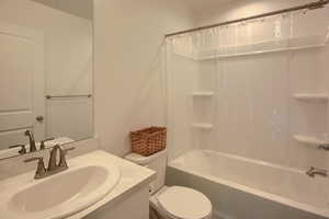 Full bathroom with vanity, shower / bath combination with curtain, and toilet