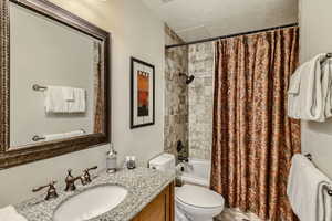 Full bathroom featuring vanity, toilet, a textured ceiling, and shower / bath combo